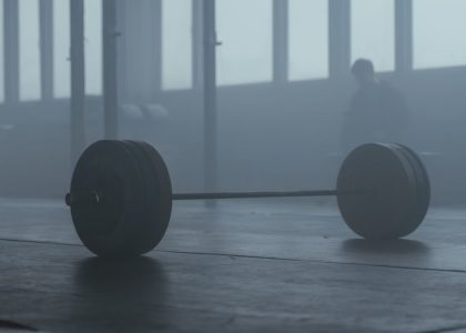 A lone barbell on the gym floor with a misty background creates a mysterious and moody ambiance.